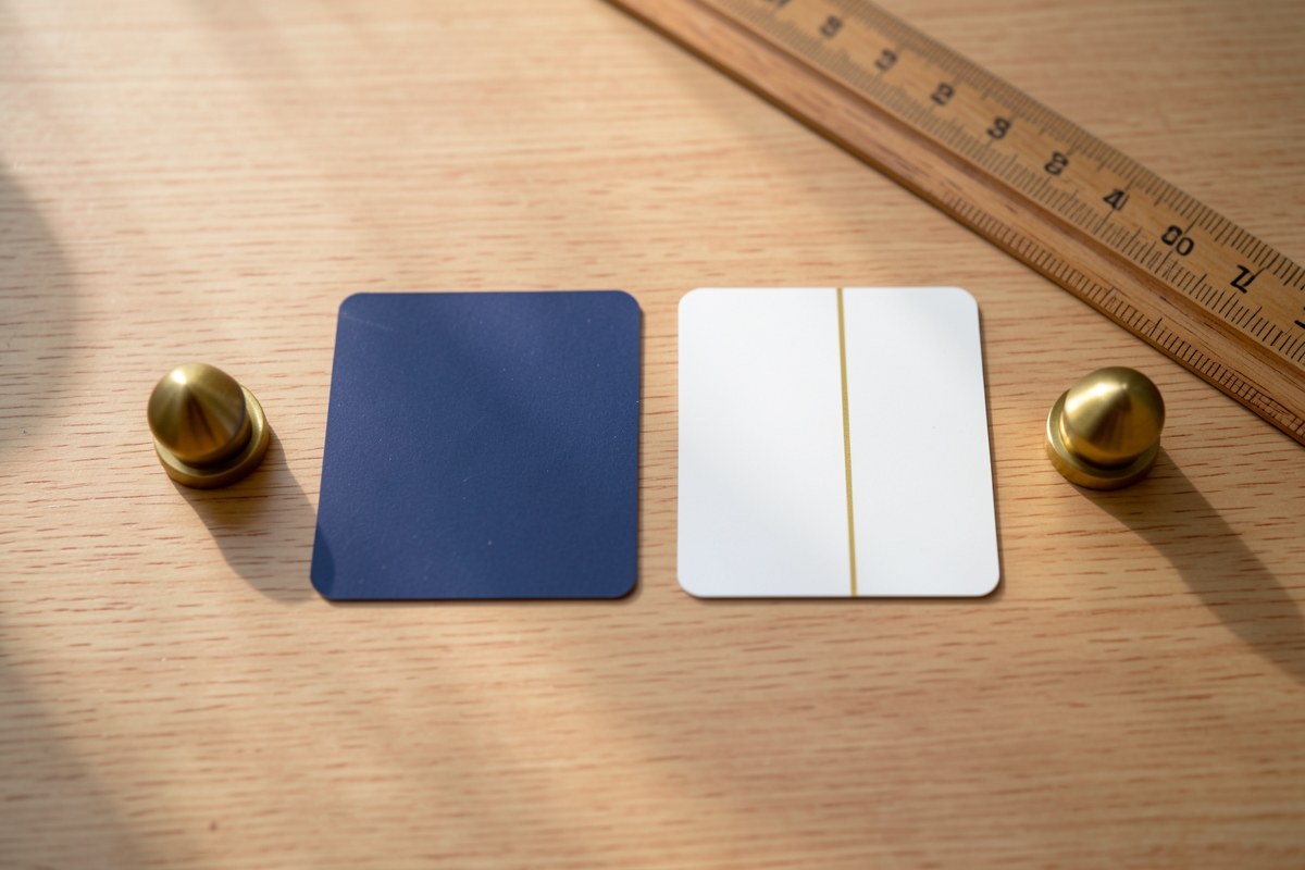 Two credit cards laid side by side on a table, with small weights and a ruler suggesting comparison, in a warm, clean setting.
